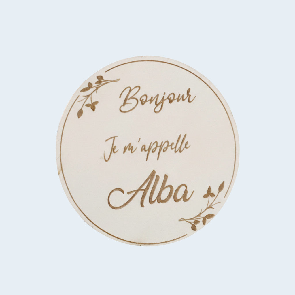 Disque de présentation nouveau-né en bois naturel gravé "Bonjour je m'appelle Alba" avec motifs de feuilles délicates.