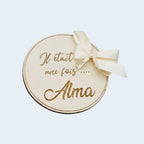 Carte de présentation naissance ronde en bois gravé avec prénom personnalisé et grand nœud en satin crème, style bohème chic.